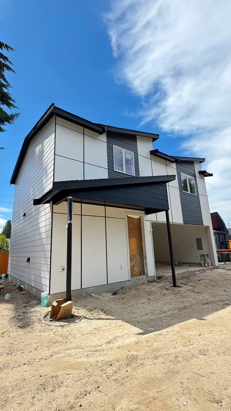 A modern two-story exterior painted white and charcoal with black trim and a covered porch.