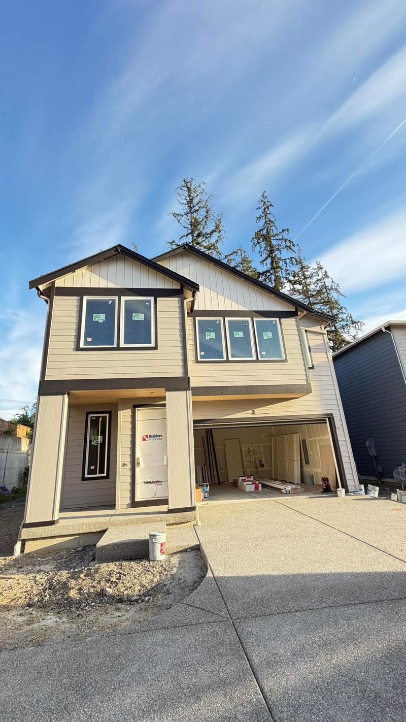 A newly painted two-story home in warm beige with dark brown trim and a finished garage opening.