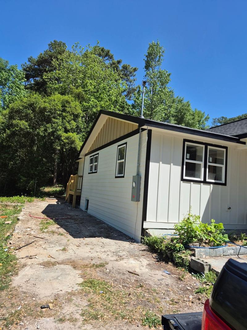 Freshly painted lap and board-and-batten siding with black window trim on a finished home exterior.